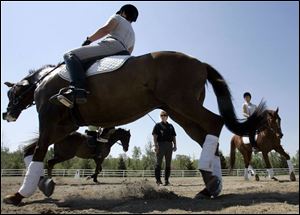 Dressage instructor Janet Harms watches riders Mandy Smith, front; Kate Marci, rear left, and Kim Sullivan putting their horses through drills in preparation for competition.
