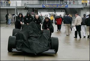 Crew members for Ed Carpenter
push his car back to the garage after practice was canceled because of the rain.