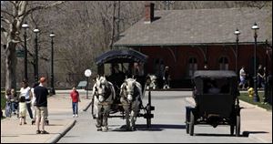 Model Ts and horse-drawn carriages tour the grounds of Greenfield Village. 