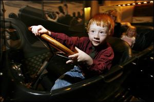 Trent Roseman, 4, of Curtice, Ohio, pretends to steer a 1917 Overland automobile at the Henry Ford Museum.
