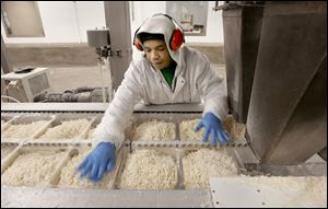 Charlie Allison spreads shredded cheese evenly before it is sealed into five-pound bags. 