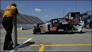 A Kodak crew member watches the wrecked car of Greg
Barnhart get towed off the track yesterday during qualifying.
