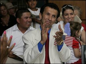 New U.S. citizens Nak Ly, Nabhan Zaitoun, and Tamar Levine, from left, celebrate their citizenship in a naturalization ceremony at Put-in-Bay on South Bass Island. The ceremony was yesterday at Perry's Victory and International Peace Memorial. The new Americans hail from 12 nations around the globe.