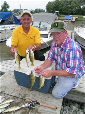 Jerry Meyers, Sr., left, and Dan Tucker hoist several jumbo-size yellow perch taken off a Lake Erie reef near Davis-Besse.