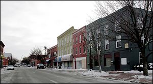 The City Hotel adorned with the awnings in the center of the photo sits across the street from a remodeled building.