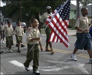 Jermayne Bush hoists the Stars and Stripes as he marches with other members of Boy Scouts of America Troop 250.