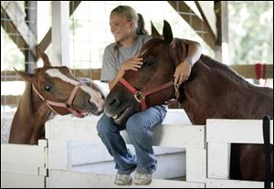 Danielle Dupler, 14, of Elmore, holds her horse Copper as Wildfire sneaks a kiss. The fair has many more horses competing this year.