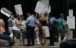 Demonstrators against domestic violence talk to Toledo police Sgt. Richard Murphy in front of Municipal Court.