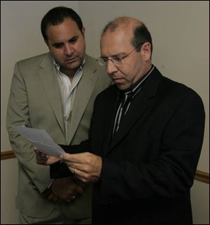 Ramy Eidi, left, of Toledo, gives Nadeem
Salem, president of the Northwest Ohio American
Arab Chamber of Commerce, a statement
concerning Mr. Eidi s mother, who is visiting her native Lebanon. Mrs. Eidi, a Toledo Lebanese-American, was visiting family and raising money for Lebanese orphans.