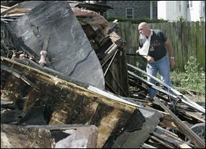 Mike Redrup scans the remains of the house at 440 Greenwood Ave. in East Toledo. He injured his arm when he jumped out of the second-floor window to flee the early morning blaze.