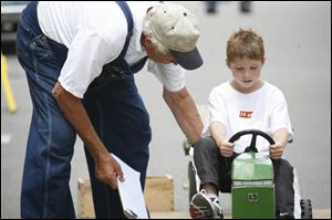 Garrison Moses, 7, prepares for a pedal-tractor pull with the guidance of Lou Mollett, a Williams County Fair board member.