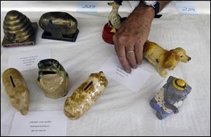 Don Speck, 79, of Maumee places a card to identify his banks for an antiques exhibit at the upcoming Lucas County Fair.