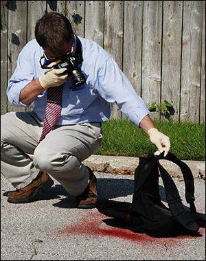 Officer Terry Cousino photographs a dye pack left by one of the robbers.