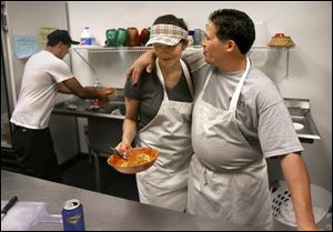 Hector Garcia gives his wife, Rachel, a hug in their restaurant, La Preciosa's. The Garcias moved to Toledo because of jobs and a lower cost of living. Mr. Garcia is also employed at Jeep.