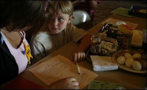Alexis Bailey, 7, looks to Elizabeth Gilda for advice with her food list.