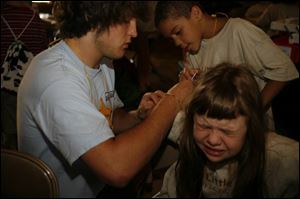 Anthony Pacholek, left, and Kory Warren give Rose Berry an injection of insulin for her diabetes as part of a day camp for kids with the Type 1 version of the condition. The camp is a service of Diabetes Youth Services based in Toledo.