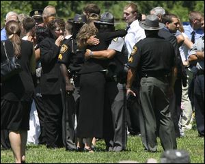 Mourners comfort each other during services at Springfield Township Cemetery for Holland police Chief Doug Kaiser.
