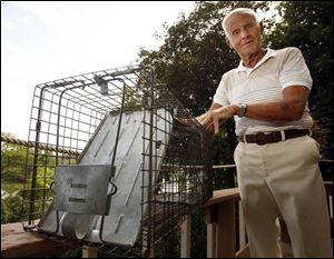 Richard Green shows off the trap that he baits with peanut butter to capture raccoons in his backyard in Maumee.

