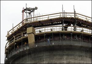 A worker puts finishing touches on the smokestack, at left, which is about 80 feet tall. 