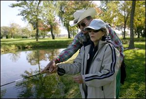 Dick Walle, one of the organizers of Reeling and Healing Inc., shows Sandra Geisert some of the finer points of fly-fishing for bass at Rockwell Springs Trout Club near Castalia while she is recovering from breast cancer. 