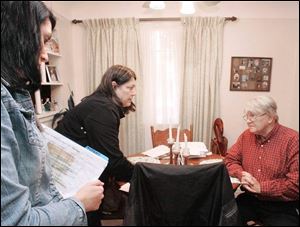 Carol Bird, left, and Sue Alex speak with Karl Oetzel, 69, a retired Jeep worker, whose Kellogg Road home was flooded on June 21. The two women helped Mr. Oetzel fill out forms.