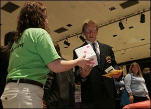 Priscilla Fleck, of the Fremont Federal Credit Union, hands Robby Yohe the die that yielded an $80 tire bill. 