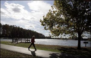 Shelly Ferris of Toledo strides through Olander Park. The park system is asking voters to renew a 0.5-mill levy next month.