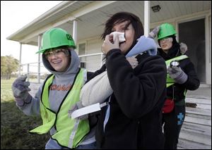 Tarah Couch, left, helps Becky Morris out of a smoke-filled house during the CERT drill at Owens Community College.