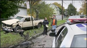 Oregon police Officer Sara Shaw, center, interviews a man whose pickup was struck by the suspects' pickup, left, after running a red light at Oak Street and Navarre Avenue.
