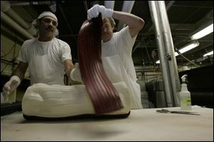 Bob Cooper, left, and Charles Smith add the stripe of color to a 20-pound log of candy.
