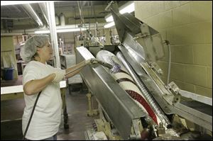 Using a special torch, Jill Nichols heats two sections to fuse them together as the candy's colors are twirled. 
