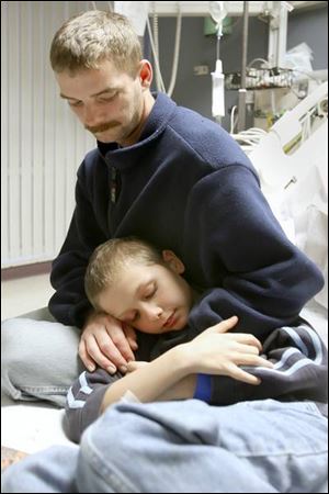Trent Cousino hugs his son, Javan, 10, in a room at St. Vincent Mercy Medical Hospital as he talks about their tale of survival in Maumee Bay.
