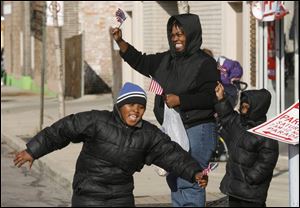 Monica Irish, center, waves at the passing parade while her sons Joel Jones, 8, at left, and Calvin, 5, grab for free candy.