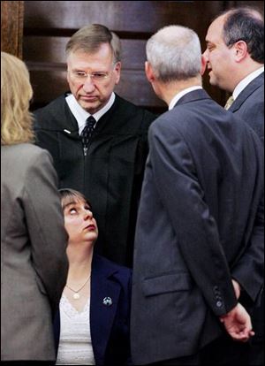 Huron County court reporter Yolanda Walton looks up at, from right, defense attorneys Kenneth Myers and Richard Drucker, and Judge Earl McGimpsey during a sidebar.