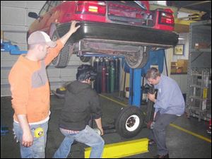 Jordan Ruffer, left, Matt Chan, and Alan Imm prepare to install the parallel parking assembly on the car.