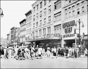 In the 1953 photograph, a crowd of shoppers is
coming and going across the intersection of Adams and
Summit Streets.