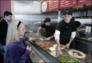 Brittany Williams specifies her burrito filling choices to Justin Schmidt.