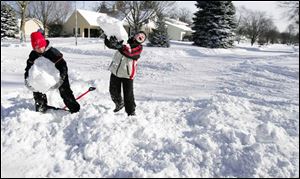 11-year-old Blake Rudolph, left, and Robert Herroon, 10, help clear snow from a neighbor s Whitechapel Street driveway.
