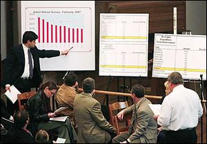Councilman Joe McNamara points to different cities on a graph being explained by Bill Franklin, Director of Public Service.