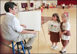 First graders Emma-Lee Segura, left, and Grace Hittler, both 7, seem a little unsure about their encounter with Walt Disney as portatryed by David Cassavar, 13.