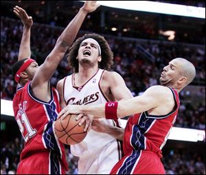 Anderson Varejao is caught between Antoine Wright, left, and Jason Kidd, who ties up the Cavalier. Kidd scored 20 points.
