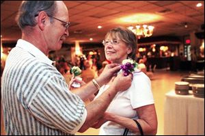 Patrick Clinger pins a corsage on the lapel of Nancy Scott, whose husband died two years ago. Ms. Scott enjoys the company of her late husband s classmates.