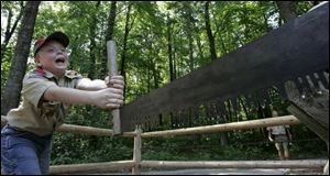 Tyler Coutcher, 11, gives it his all on one end of a two-man bucksaw at a camp demonstration. He is a member of Troop 100. 