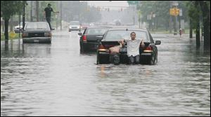 Collingwood Boulevard looked like a lake yesterday afternoon. Twins Darnell, left, and Donnie Hall, 14, provide some push power to a stalled auto.
