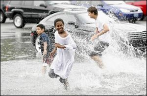 There were some who found fun in the flood, however; Johnnie Barringer, left, Justice Womack, foreground, and
Miguel Neilson enjoy a splash in an Old West End parking lot.