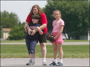 Julie LHeureux helps her son Jason LHeureux wait for a ball to come to him out in the field with his sister, Jessica LHeureux, who's ready to lend a hand if needed. 
