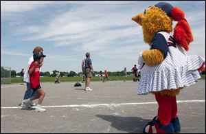 Schyler Young gets some encouragement from Muddonna, one of the Toledo Mud Hen baseball team's mascots who came out for the Miracle League of Northwest Ohio's finals. Schyler is accompanied by volunteer Patricia Pokrzywa on the trip around the bases. 
