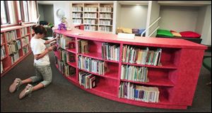 Dair Yorde, a library page, stocks the circular shelves with exciting and inviting tomes.