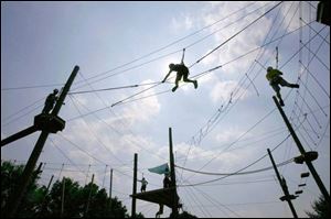Niv Koren, center, of Israel climbs fearlessly on high ropes at the 2007 World Oncology Camp at YMCA Storer Camps in Napoleon, Mich. After all, Niv and 47 other children have stared down far worse: cancer. 