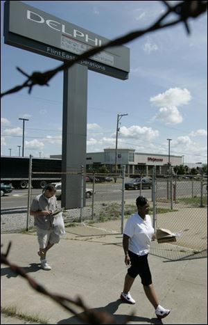 Workers enter Delphi Corp.'s operations in Flint, Mich. They are among the workers who must decide to take a wage cut.